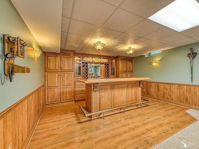 255 Maywood Ave, Monroe, MI 48162 - kitchen with wainscoting, brown cabinetry, light wood-style floors, wood walls, and a center island
