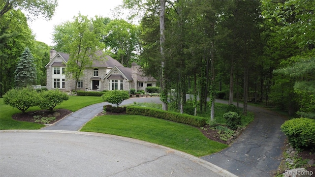 4270 Argenta Dr, Brighton, MI 48116 - view of front of house featuring stone siding, a chimney, a front yard, and asphalt driveway