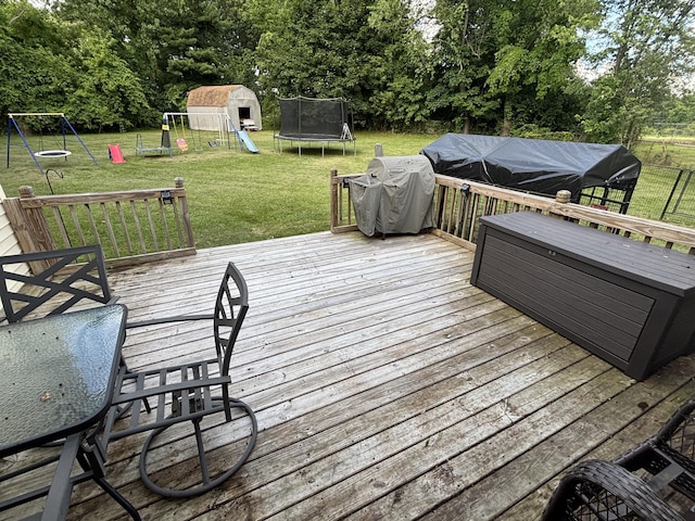 137 Apperson Rd, Battle Creek, MI 49015 - wooden terrace featuring a trampoline, a playground, a lawn, area for grilling, and view of wooded area