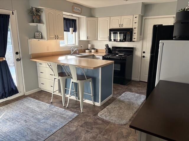 137 Apperson Rd, Battle Creek, MI 49015 - kitchen with black appliances, open shelves, a peninsula, white cabinetry, and a kitchen breakfast bar