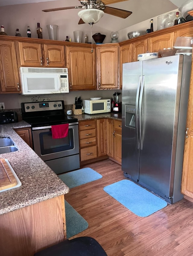 5344 Wheat Way Ave, Swartz Creek, MI 48473 - kitchen featuring appliances with stainless steel finishes, light wood-type flooring, a ceiling fan, dark stone countertops, and brown cabinetry
