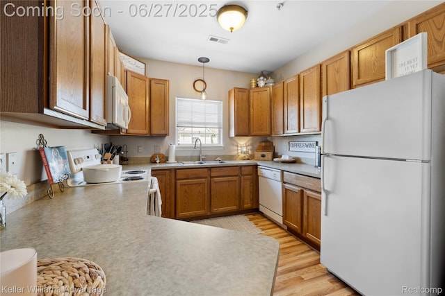 3201 Addington Dr, Commerce Twp, MI 48390 - kitchen featuring white appliances, light countertops, decorative light fixtures, light wood-style flooring, and brown cabinets