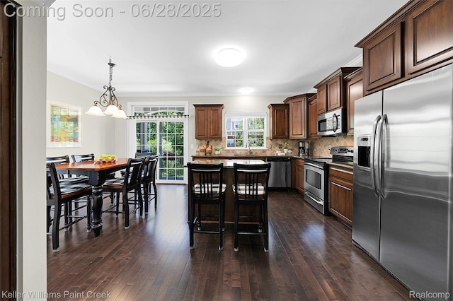 6014 Windemere Ln, Shelby Twp, MI 48316 - kitchen with appliances with stainless steel finishes, ornamental molding, dark wood finished floors, tasteful backsplash, and a kitchen bar