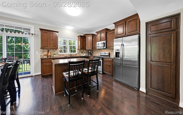 6014 Windemere Ln, Shelby Twp, MI 48316 - kitchen featuring stainless steel appliances, a kitchen island, decorative backsplash, dark wood-type flooring, and crown molding
