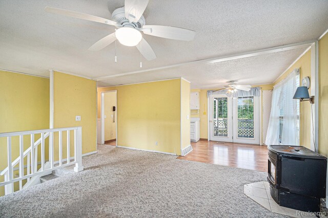 367 N Morrison Rd, West Branch, MI 48661 - unfurnished living room with a wood stove, a ceiling fan, carpet flooring, and a textured ceiling