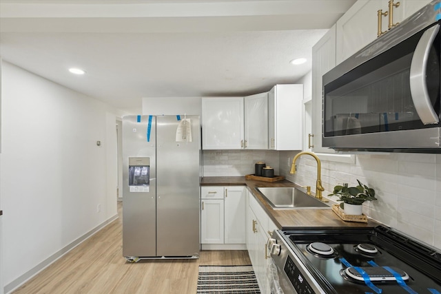 3736 Michael Ave SW, Wyoming, MI 49509 - kitchen with stainless steel appliances, light wood-style flooring, backsplash, white cabinetry, and recessed lighting