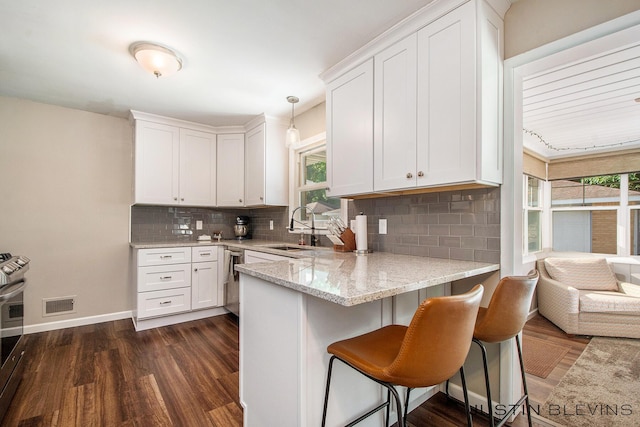 1538 10th St NW, Grand Rapids, MI 49504 - kitchen with white cabinets, tasteful backsplash, light stone countertops, and a peninsula