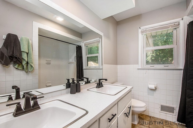 1538 10th St NW, Grand Rapids, MI 49504 - bathroom featuring tile walls, a shower with shower curtain, healthy amount of natural light, double vanity, and wainscoting