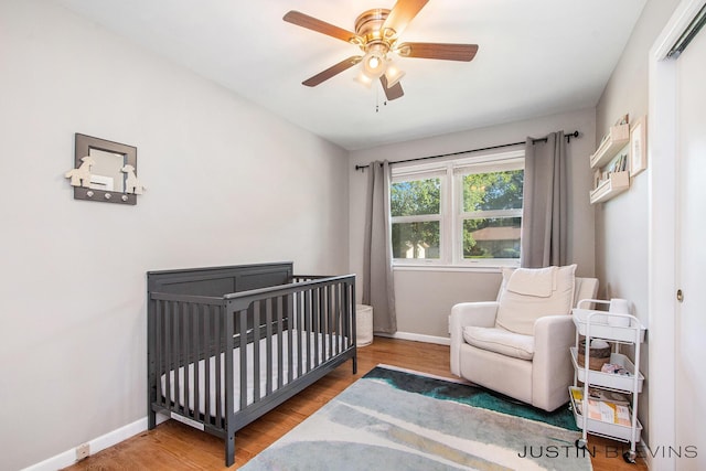 1538 10th St NW, Grand Rapids, MI 49504 - bedroom featuring wood finished floors, a crib, and ceiling fan