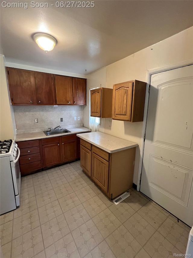 6832 Cornell St, Taylor, MI 48180 - kitchen with white range with gas cooktop, light countertops, and brown cabinetry