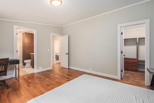 80150 46th Ave, Coloma, MI 49038 - unfurnished bedroom featuring crown molding, wood finished floors, a spacious closet, a textured ceiling, and connected bathroom