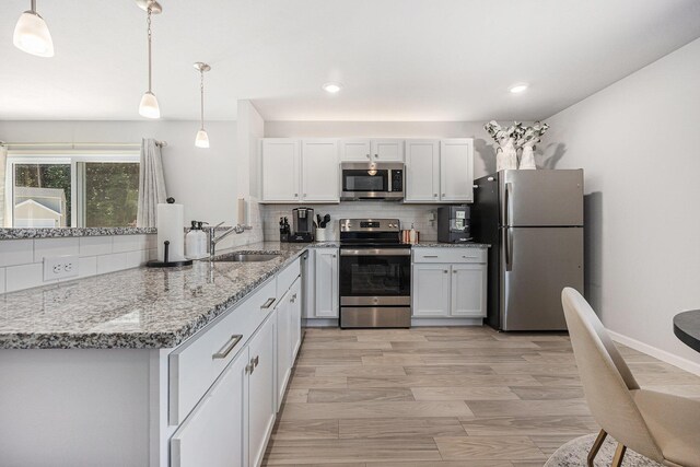 374 Lotz Ct, Wayland, MI 49348 - kitchen featuring appliances with stainless steel finishes, decorative backsplash, light stone countertops, hanging light fixtures, and recessed lighting