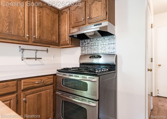 646 Alan Dr, Lake Orion, MI 48362 - kitchen featuring double oven range, under cabinet range hood, backsplash, brown cabinets, and light countertops