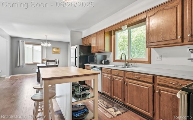 646 Alan Dr, Lake Orion, MI 48362 - kitchen with dishwasher, brown cabinets, a chandelier, wood finished floors, and stove