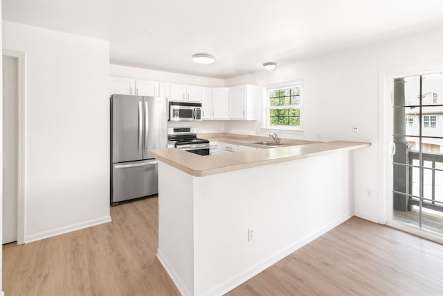 3046 Barclay Way, Ann Arbor, MI 48105 - kitchen with stainless steel appliances, light wood-style floors, a peninsula, light countertops, and white cabinetry