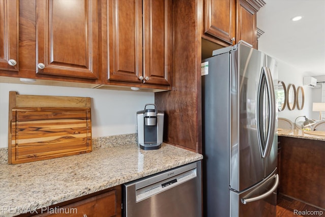 5959 Alan Dr Unit 53, Brighton, MI 48116 - kitchen with appliances with stainless steel finishes, light stone counters, wood finished floors, brown cabinets, and a wall mounted air conditioner