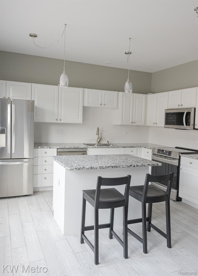 25493 Saint James, Southfield, MI 48075 - kitchen with stainless steel appliances, white cabinetry, decorative light fixtures, light stone countertops, and a center island