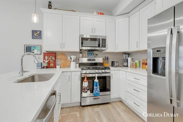 605 Bedford Falls Dr, Sparta, MI 49345 - kitchen featuring stainless steel appliances, white cabinets, tasteful backsplash, pendant lighting, and light wood-style floors