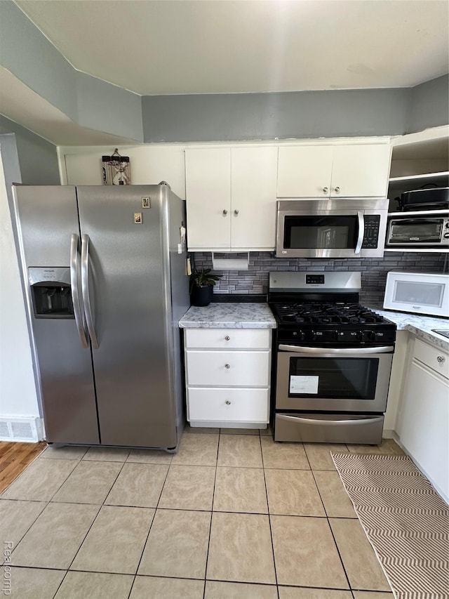 32302 Ryan Rd, Warren, MI 48092 - kitchen with stainless steel appliances, light countertops, tasteful backsplash, white cabinets, and light tile patterned flooring
