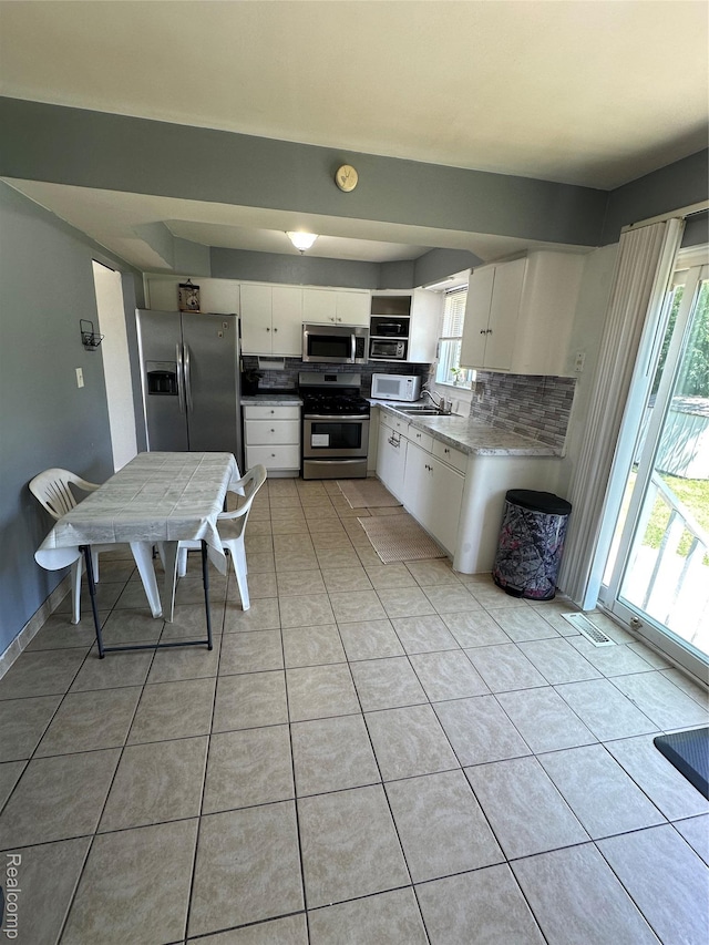32302 Ryan Rd, Warren, MI 48092 - kitchen with appliances with stainless steel finishes, backsplash, white cabinetry, and light tile patterned floors