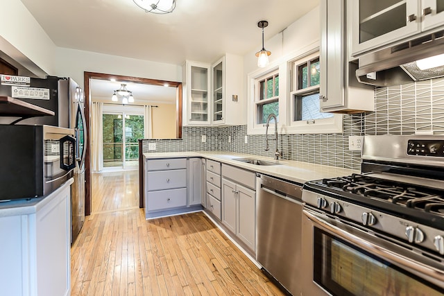 324 Highlake Ave, Ann Arbor, MI 48103 - kitchen with stainless steel appliances, under cabinet range hood, gray cabinetry, light wood-style floors, and backsplash