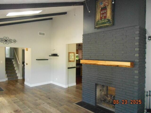 1090 Cadet Ln, Kalamazoo, MI 49009 - unfurnished living room with high vaulted ceiling, wood finished floors, a brick fireplace, stairs, and beam ceiling