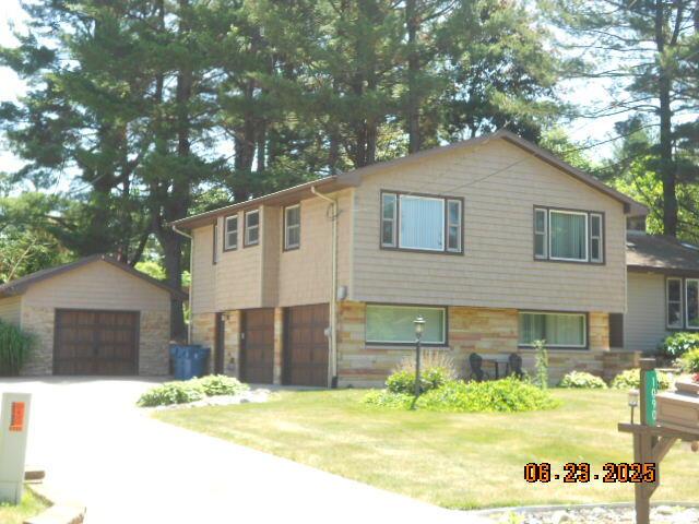 1090 Cadet Ln, Kalamazoo, MI 49009 - view of front of house with a garage, an outbuilding, a front yard, and stone siding