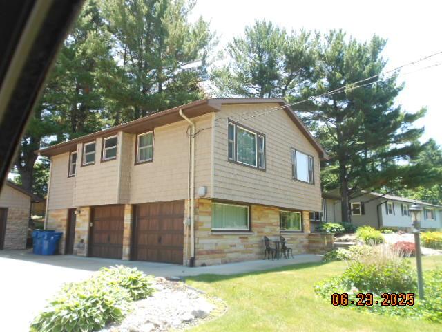 1090 Cadet Ln, Kalamazoo, MI 49009 - view of side of home with stone siding, an attached garage, and driveway