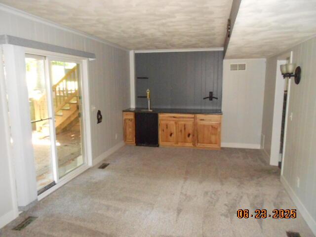1090 Cadet Ln, Kalamazoo, MI 49009 - unfurnished living room with crown molding, wet bar, light carpet, and stairs