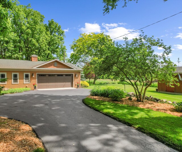 928 Curtis Rd, Quincy, MI 49082 - view of front of home featuring an attached garage, asphalt driveway, a front yard, and a chimney