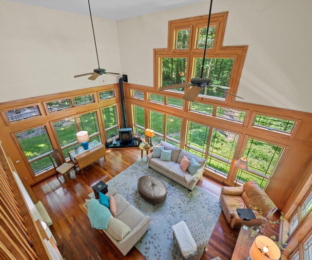 928 Curtis Rd, Quincy, MI 49082 - living area featuring a wood stove, a ceiling fan, a towering ceiling, and wood finished floors