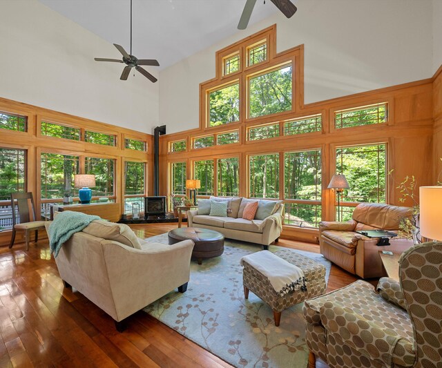 928 Curtis Rd, Quincy, MI 49082 - living room featuring a wood stove, ceiling fan, high vaulted ceiling, and hardwood / wood-style floors