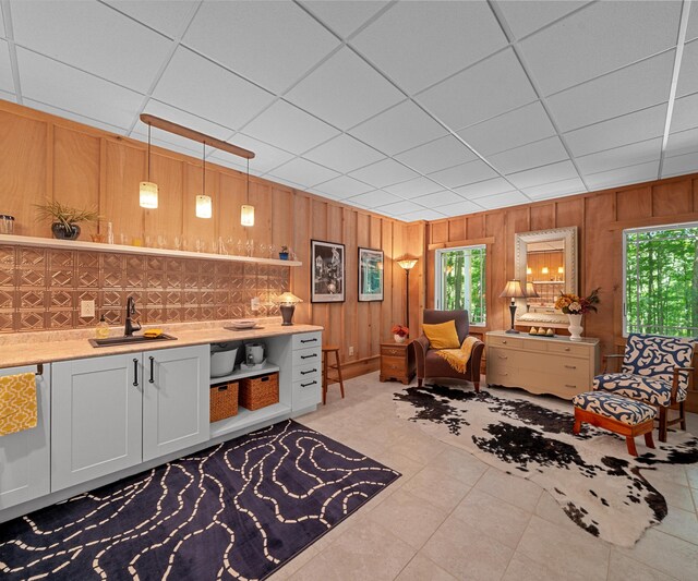 928 Curtis Rd, Quincy, MI 49082 - living room with bar with sink, wooden walls, light tile patterned flooring, and a drop ceiling