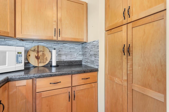 2606 S Saint Anthony St, Jackson, MI 49203 - kitchen view of white microwave, dark countertops, tasteful backsplash, and light brown cabinets