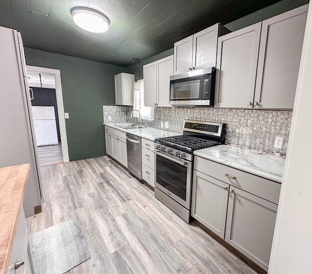148 N Eddy St, Merrill, MI 48637 - kitchen with stainless steel appliances, decorative backsplash, and light wood-style floors
