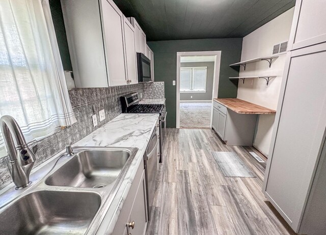 148 N Eddy St, Merrill, MI 48637 - kitchen with black microwave, open shelves, light wood-type flooring, tasteful backsplash, and wood counters