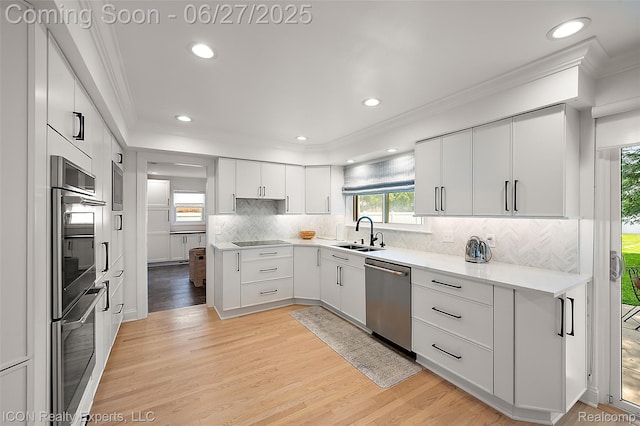 28440 Brooks Ln, Southfield, MI 48034 - kitchen featuring appliances with stainless steel finishes, ornamental molding, light wood-style flooring, decorative backsplash, and light countertops