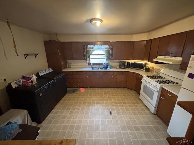 2220 Alice St, Farwell, MI 48622 - kitchen with white gas stove, under cabinet range hood, light countertops, stainless steel microwave, and independent washer and dryer
