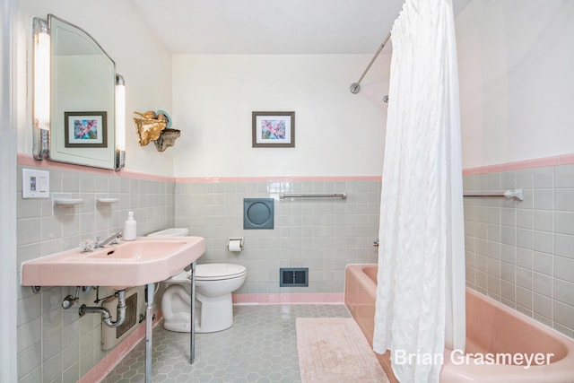 539 Overbrook Ln SE, Grand Rapids, MI 49507 - bathroom featuring shower / tub combo with curtain, tile walls, a wainscoted wall, and tile patterned flooring