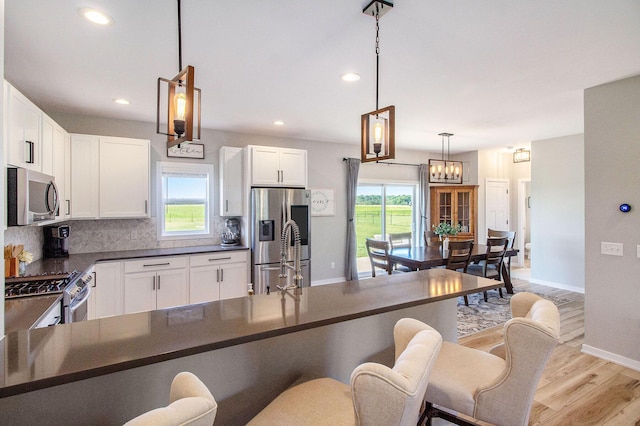 11539 Warrior Trl, Grass Lake, MI 49240 - kitchen with appliances with stainless steel finishes, dark countertops, light wood finished floors, tasteful backsplash, and a breakfast bar