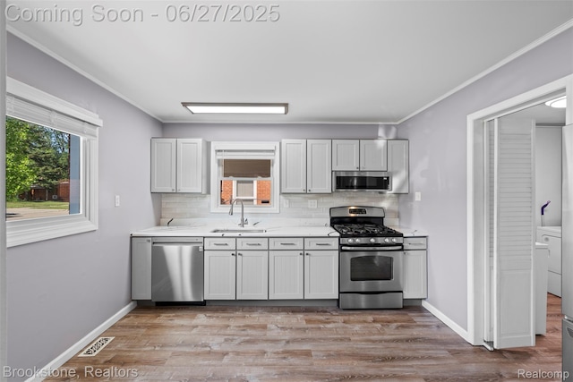 1293 Moulin Ave, Madison Heights, MI 48071 - kitchen with stainless steel appliances, backsplash, light countertops, light wood-type flooring, and crown molding
