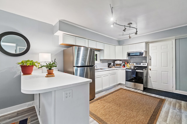 1645 Chlebus St, Jackson, MI 49203 - kitchen featuring stainless steel appliances, light countertops, light wood-type flooring, white cabinetry, and a peninsula