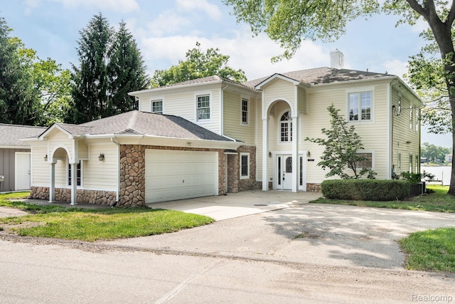 3831 Woodland Dr, Highland, MI 48356 - view of front of house with an attached garage, stone siding, concrete driveway, a chimney, and a shingled roof