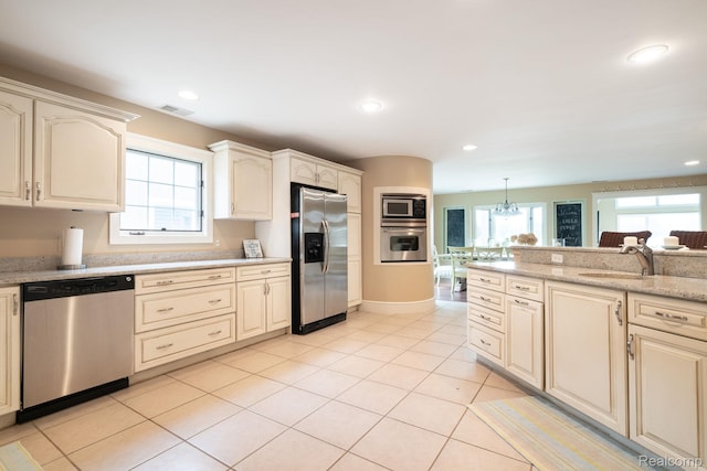3831 Woodland Dr, Highland, MI 48356 - kitchen featuring appliances with stainless steel finishes, healthy amount of natural light, recessed lighting, light tile patterned floors, and a chandelier
