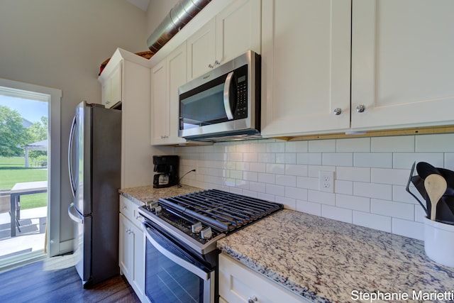 675 Terrace Point Dr, Muskegon, MI 49440 - kitchen featuring stainless steel appliances, white cabinets, backsplash, light stone countertops, and dark wood-style floors