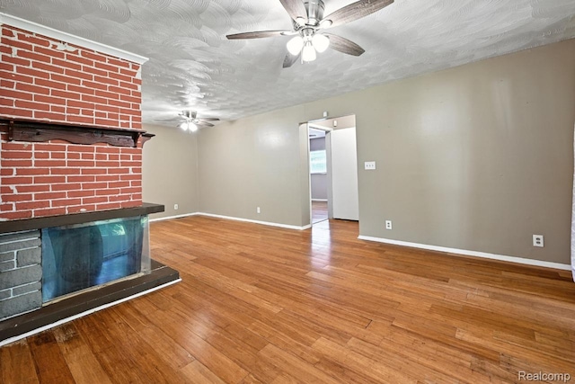 1935 Carmanbrook Pkwy, Flint, MI 48507 - unfurnished living room featuring ceiling fan, wood finished floors, a fireplace, and a textured ceiling