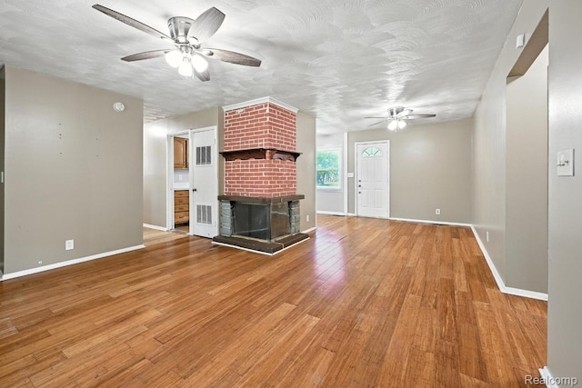 1935 Carmanbrook Pkwy, Flint, MI 48507 - unfurnished living room featuring a ceiling fan, a brick fireplace, and light wood finished floors