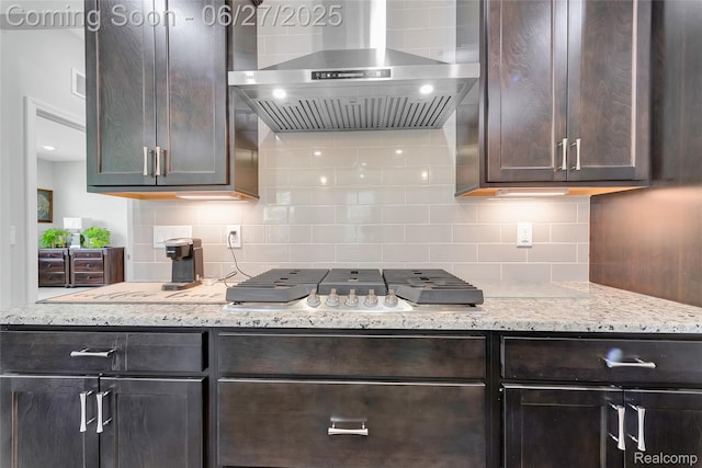 38731 Chasewood Ct, Farmington Hills, MI 48335 - kitchen featuring wall chimney range hood, stainless steel gas cooktop, backsplash, dark brown cabinetry, and light stone countertops