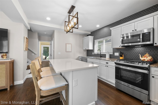 389 Kercheval Ave, Grosse Pointe, MI 48236 - kitchen featuring appliances with stainless steel finishes, dark wood-style flooring, a kitchen island, decorative backsplash, and recessed lighting