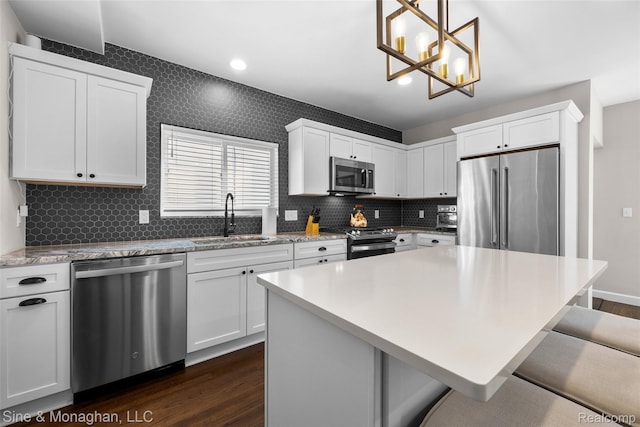 389 Kercheval Ave, Grosse Pointe, MI 48236 - kitchen featuring appliances with stainless steel finishes, dark wood-style floors, a kitchen bar, decorative backsplash, and a chandelier
